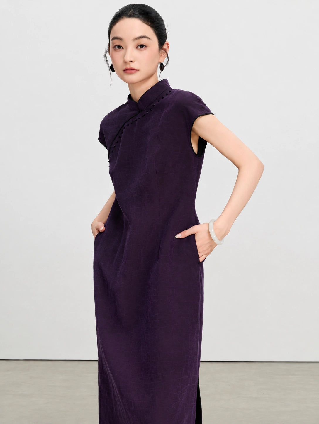 Close view of the tailored waist and side pockets on a purple gambiered silk qipao dress.