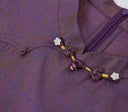 Close-up of the floral bead accents, knotted closure and concealed zipper on the silk qipao dress.