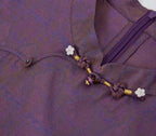 Close-up of the floral bead accents, knotted closure and concealed zipper on the silk qipao dress.