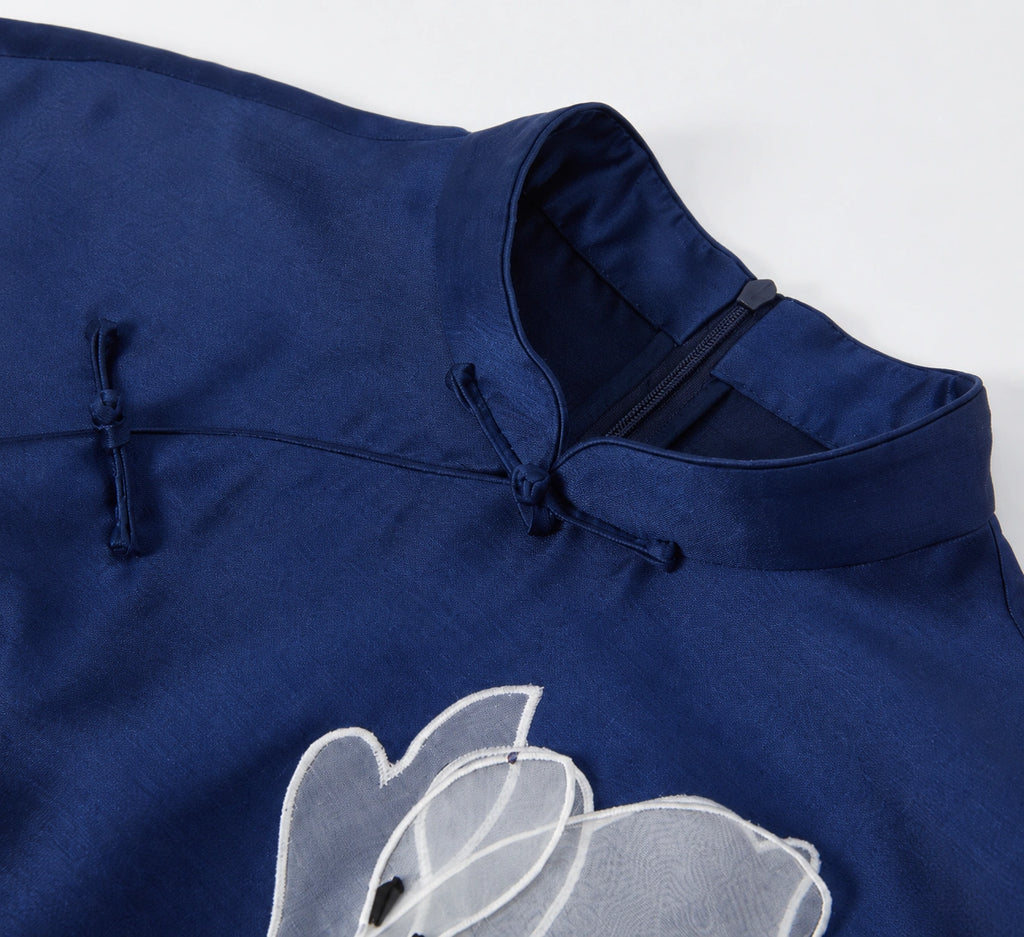 Close-up of the navy qipao stand collar, knotted frog closures and magnolia embroidery
