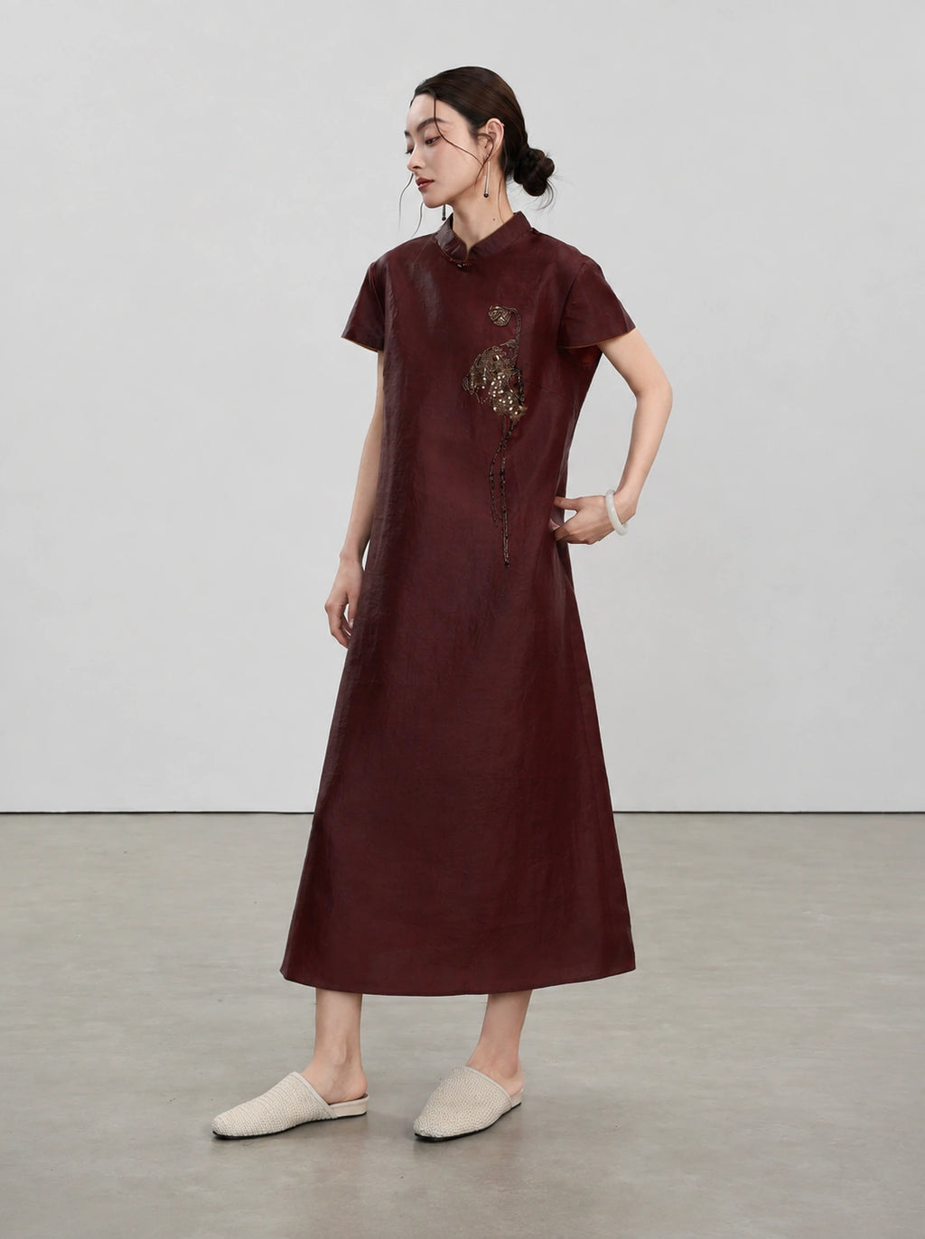 Three-quarter full-length view of the relaxed red A-line qipao with embroidered detailing