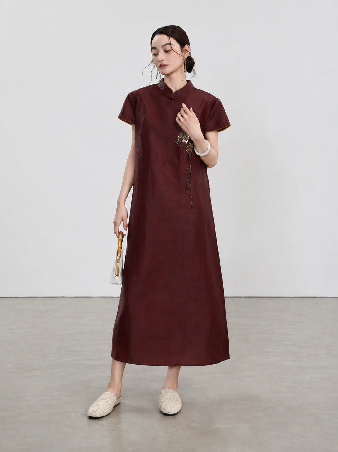 Full-length view of the oxblood-red Xiangyunsha qipao with lotus-inspired embroidery
