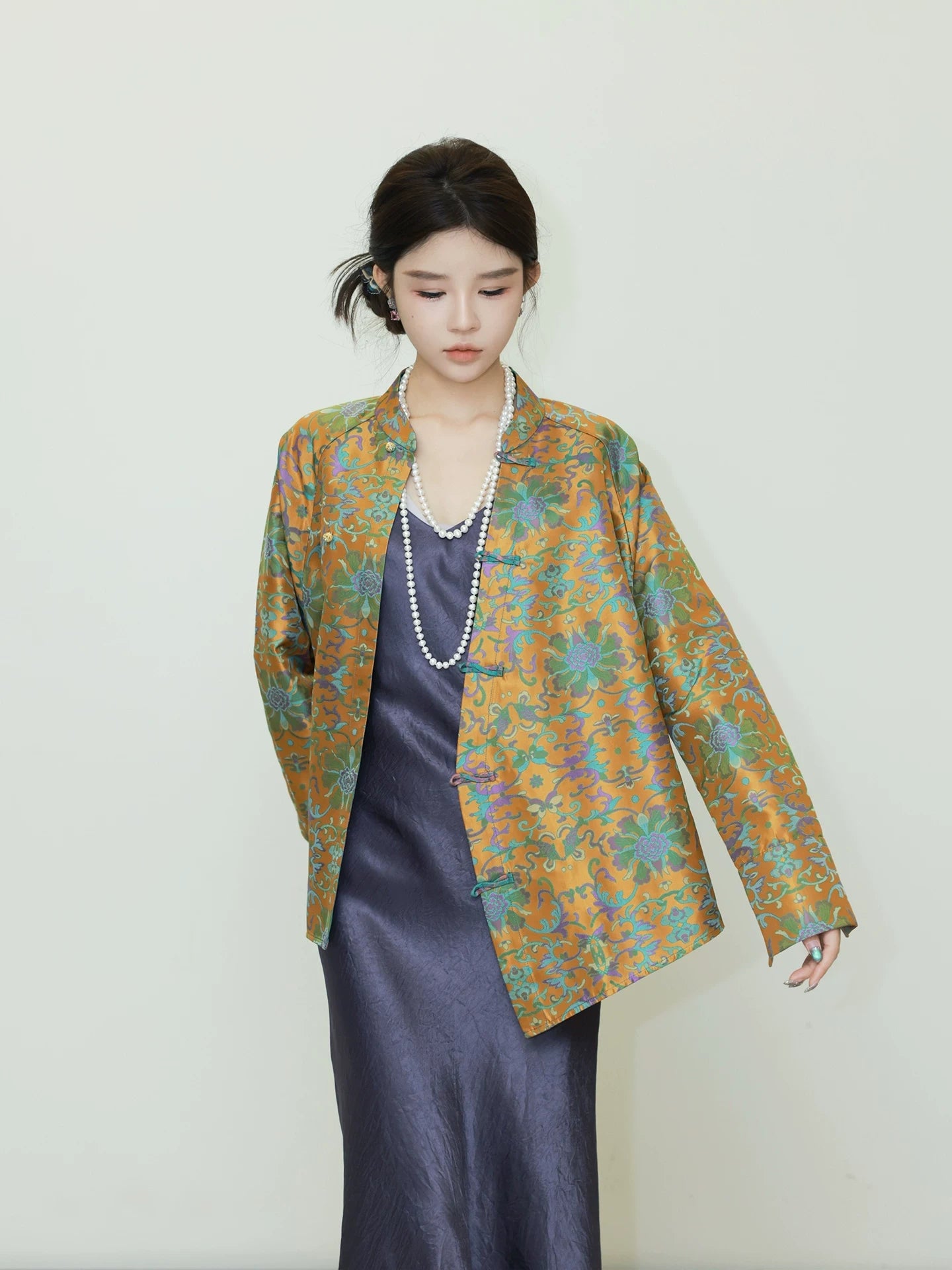 Close-up of a model wearing a reversible Chinese-inspired mulberry silk jacket with an ornate floral pattern