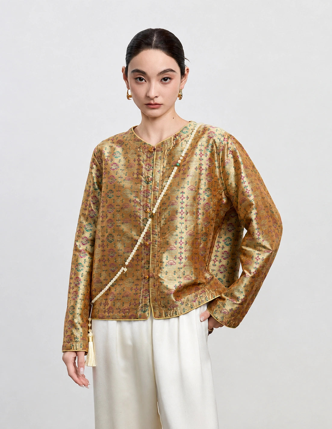 Front detail of the antique gold reversible silk jacket with a round neckline and decorative buttons.