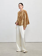 Model wearing the antique gold side of the reversible Shu brocade silk jacket with white trousers.
