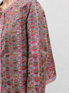 Close-up of the dusty mauve Shu brocade silk fabric with colorful traditional woven motifs.