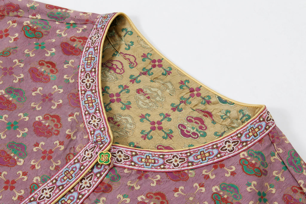 Close-up of the reversible Shu brocade jacket neckline showing antique gold and dusty mauve woven patterns.