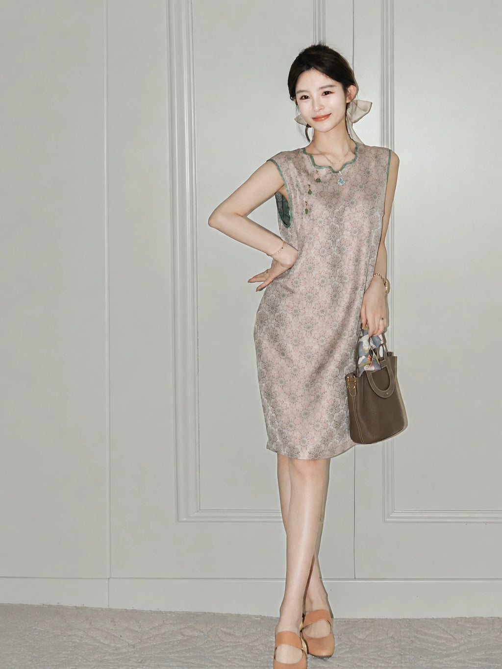 Woman wearing the blush-pink side of the reversible Song brocade silk dress with green trim.