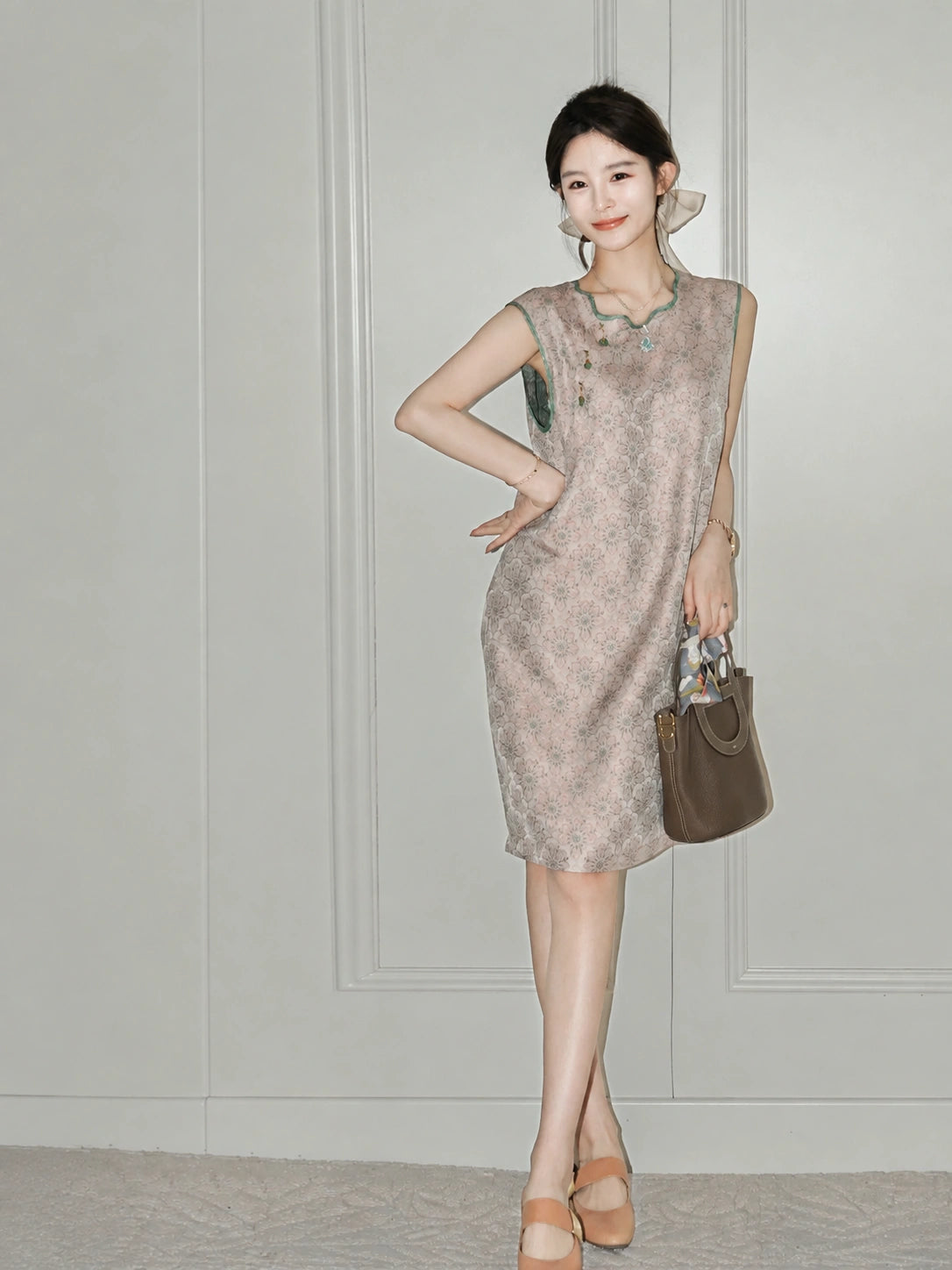 Woman wearing the blush-pink side of the reversible Song brocade silk dress with green trim.