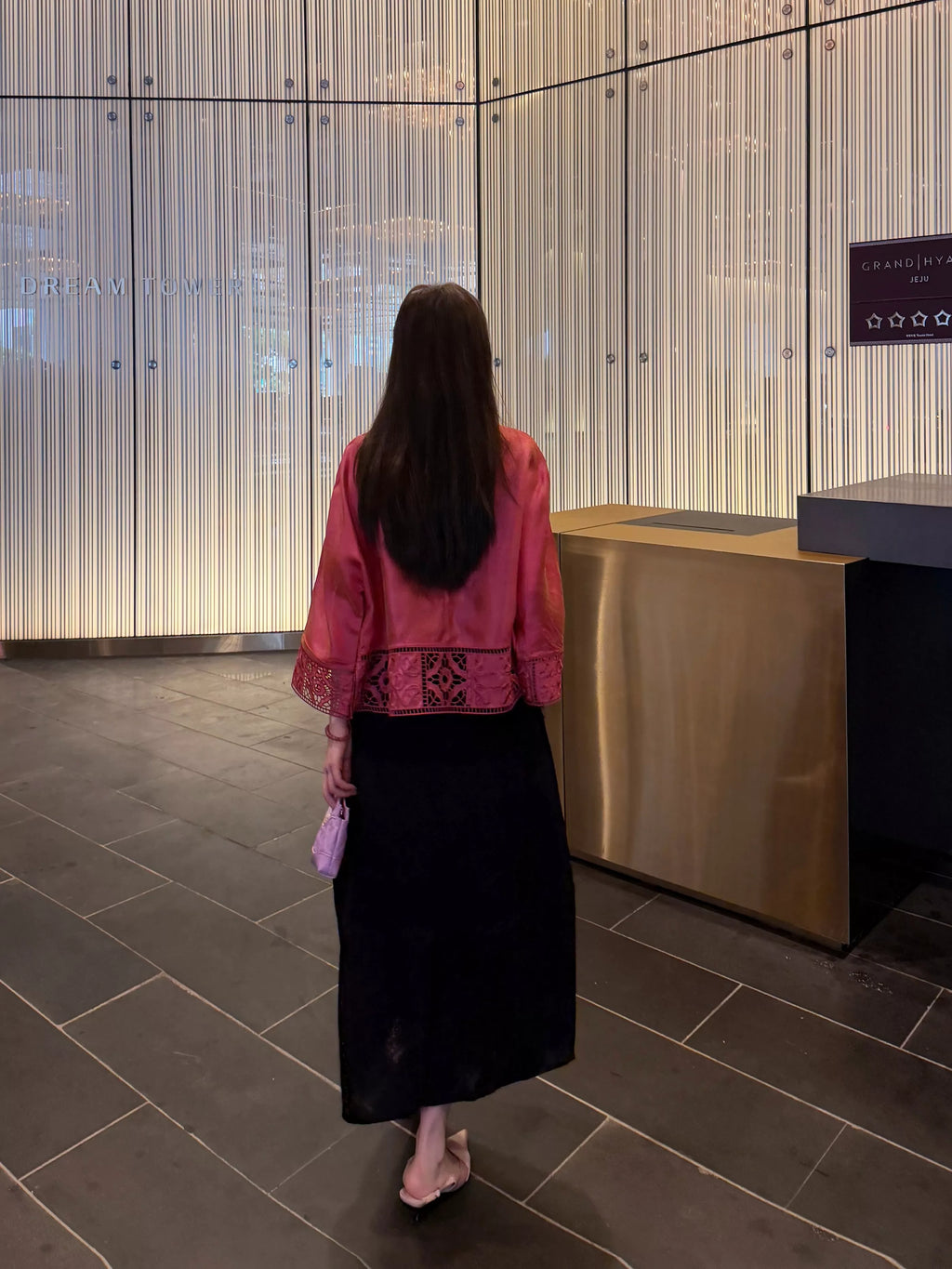 Back view of a rose pink silk jacket with openwork hem and straight sleeves