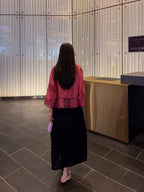 Back view of a rose pink silk jacket with openwork hem and straight sleeves
