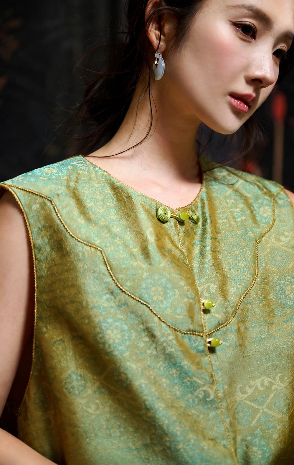 Close-up of the round neckline, curved yoke and luminous celadon silk jacquard