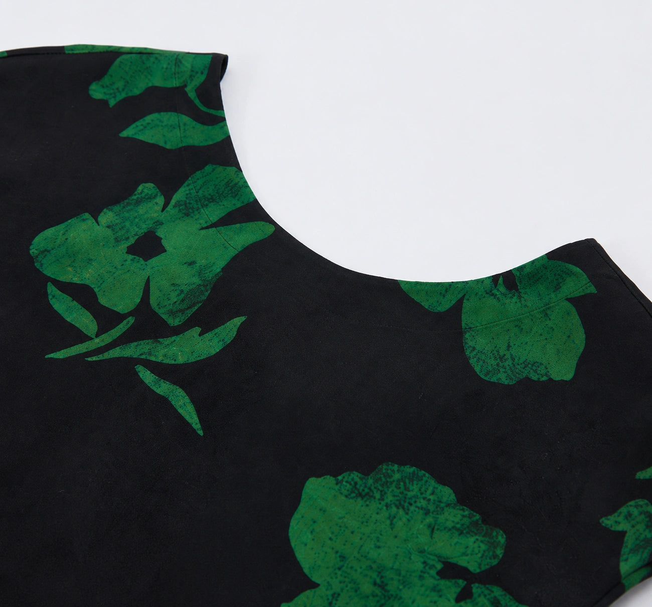 Close-up of the round neckline and green botanical print on black mulberry silk.