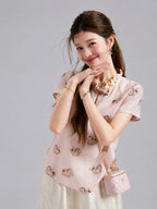 Gambiered Silk silk top featuring playful pony motifs, a ruffled collar and a jeweled button closure