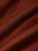 Close-up of the lustrous textured surface of rust-brown 100% mulberry silk fabric.