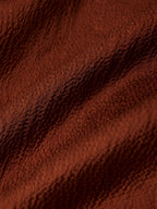 Close-up of the lustrous textured surface of rust-brown 100% mulberry silk fabric.