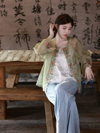 Model wearing a sage green embroidered mulberry silk overshirt over a white top and light blue jeans