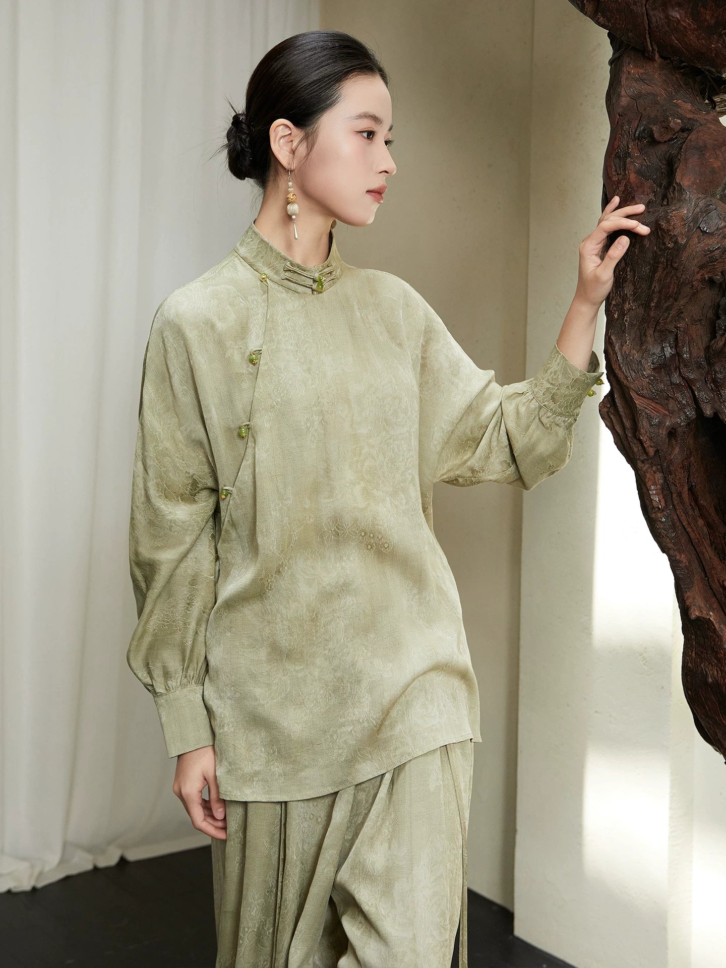 Side profile of the Sage Green Mandarin Collar Lyocell Blend Blouse showing the elegant drape and asymmetrical frog-button design.