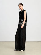 Side view of a black embroidered velvet vest showing its relaxed silhouette and translucent silk hem.