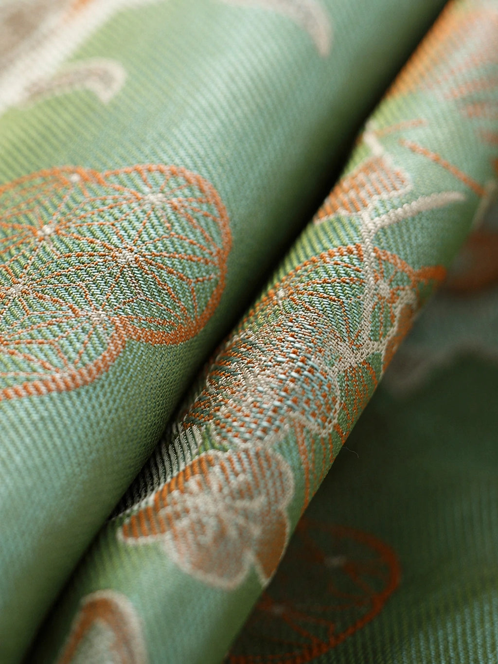 Close-up of jade green Shu brocade silk with ivory and terracotta butterfly and botanical motifs
