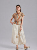 Model wearing a Gambiered Silk orange-gold Shu brocade top with ivory wide-leg trousers