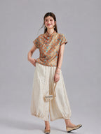 Model wearing a Gambiered Silk orange-gold Shu brocade top with ivory wide-leg trousers