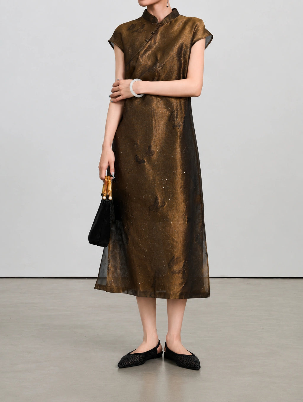 Styled view of the silk-blend qipao showing its stand collar, butterfly motifs and fine shimmer