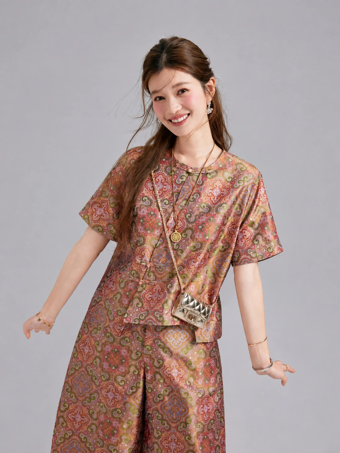 Model wearing a coordinated mulberry silk jacket and cropped wide-leg trousers in an ornate brocade pattern.