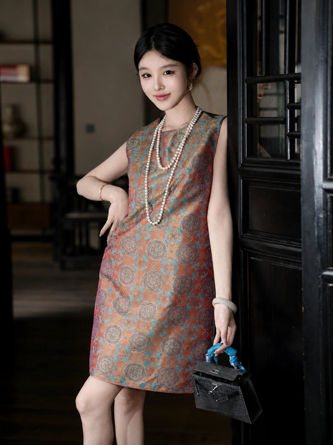 Full-length lifestyle view of a model wearing a relaxed vermilion Shu brocade summer dress.