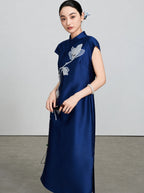 Three-quarter view showing the smooth silk-wool fabric and magnolia embroidery of the navy qipao