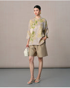 Front view of the taupe silk blouse featuring green foliage, a relaxed silhouette and rounded hem