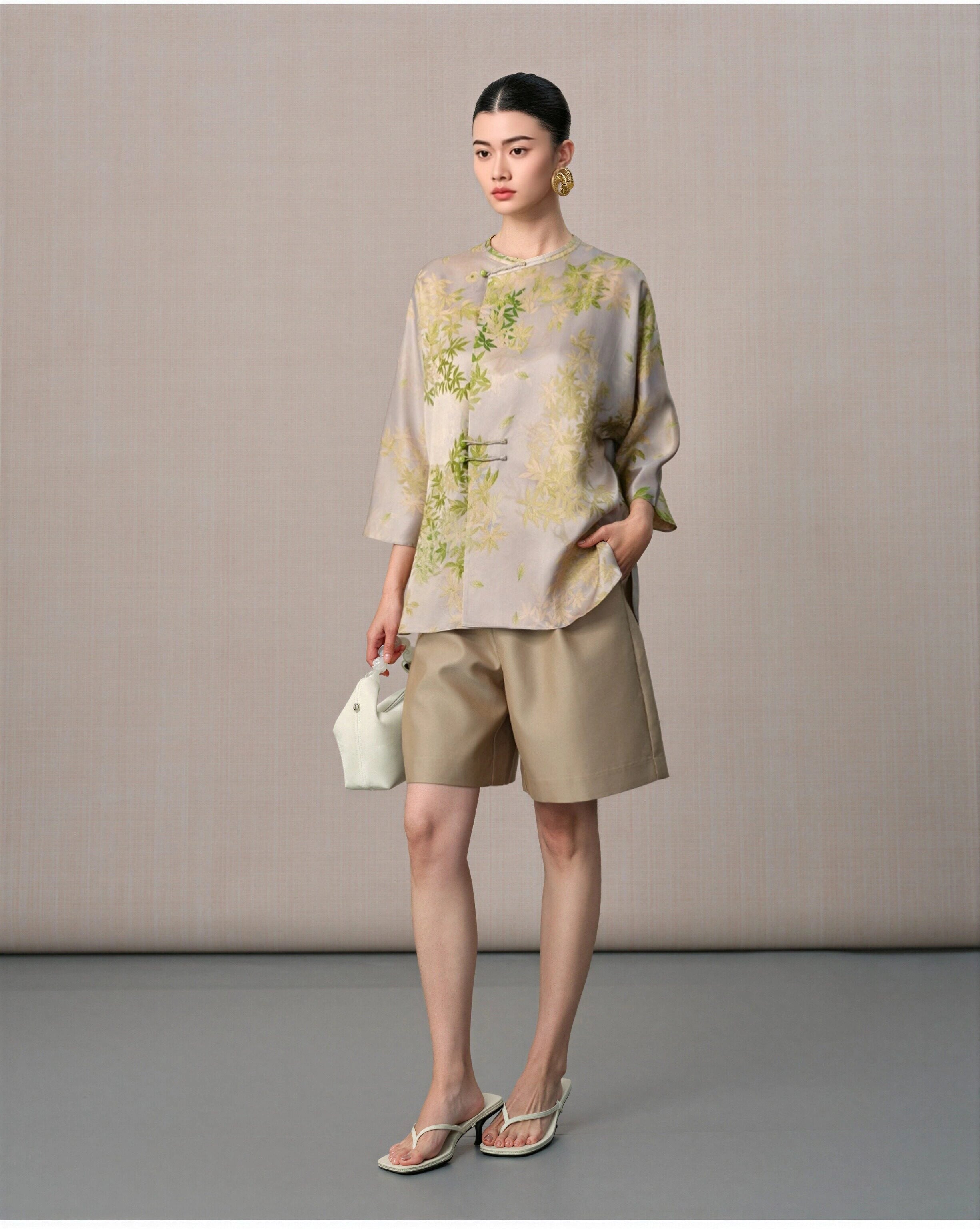 Front view of the taupe silk blouse featuring green foliage, a relaxed silhouette and rounded hem