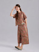 Model wearing a multicolored Gambiered Silk Shu brocade set with a short silk jacket and cropped wide-leg trousers.