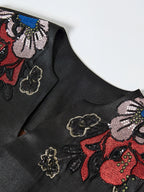 Close-up of the notched V-neck and colorful floral embroidery on the black silk dress