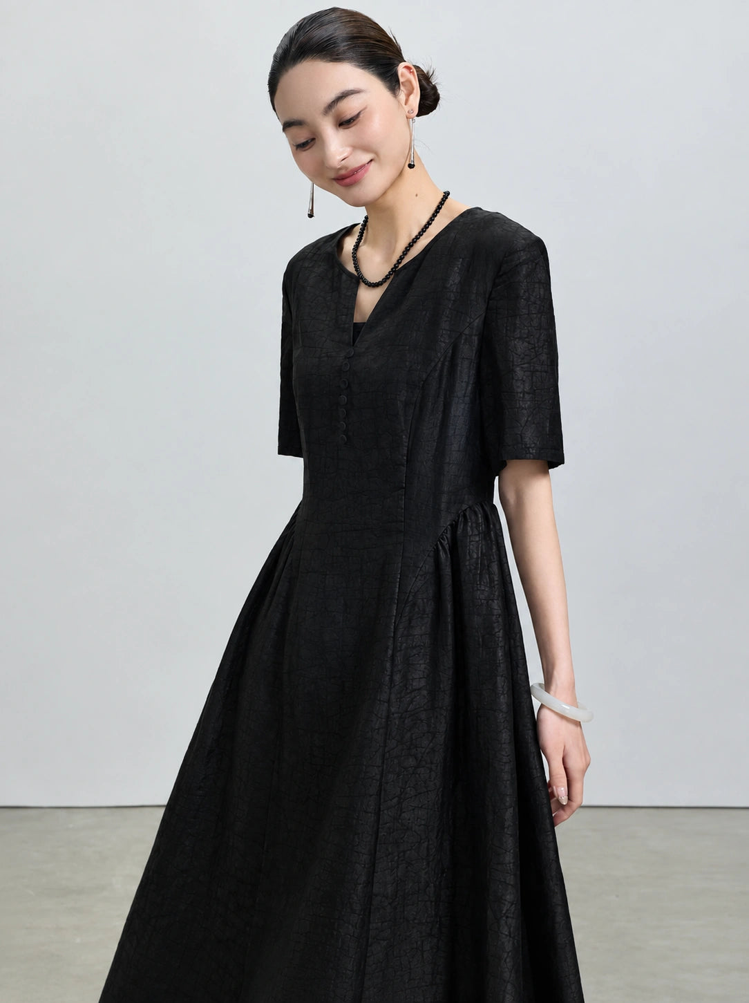 Three-quarter view of the layered V-neck, covered buttons and crackled Xiangyunsha texture