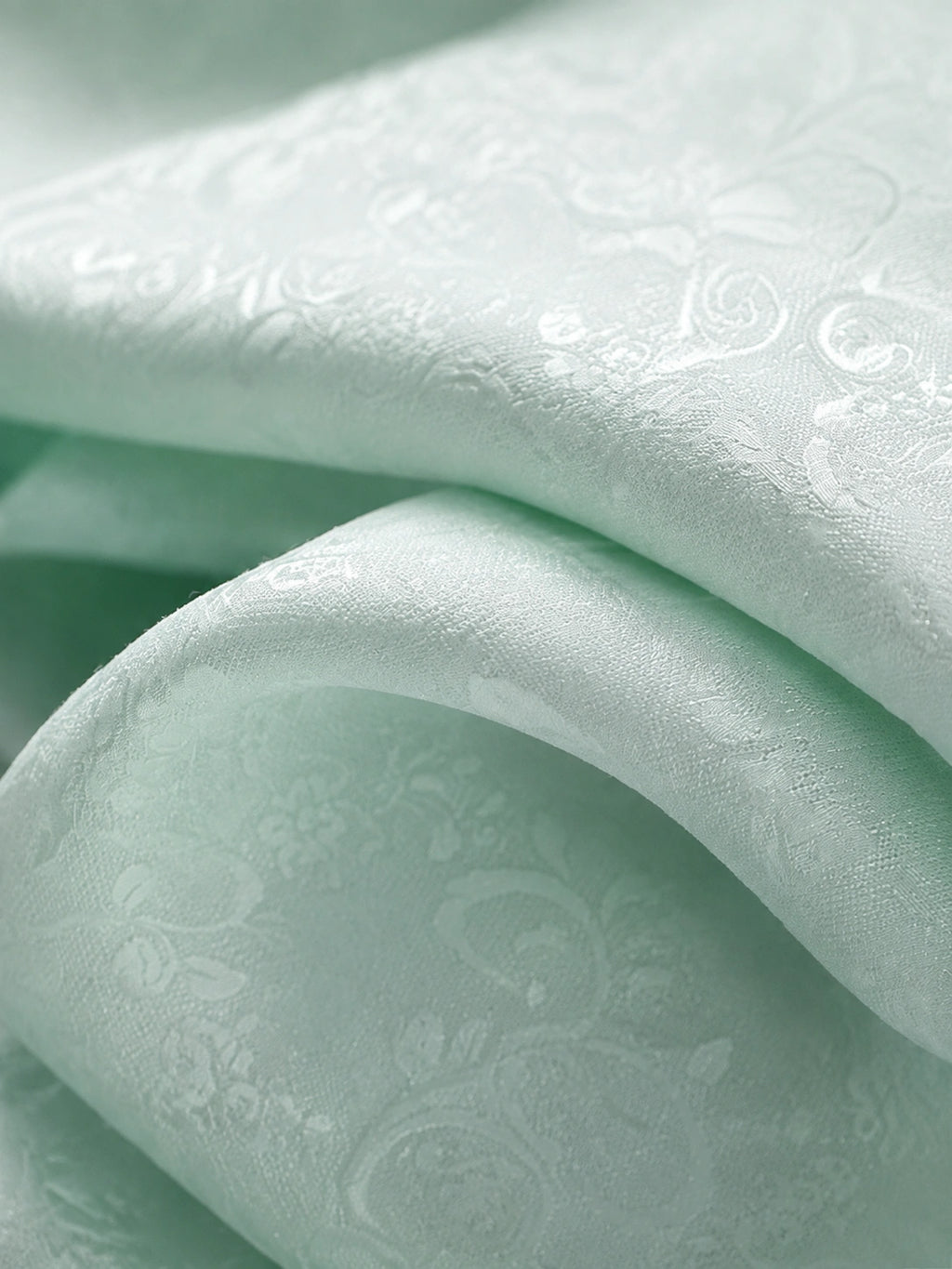 Close-up of lightweight water blue jacquard fabric with tonal vintage leaf and floral motifs