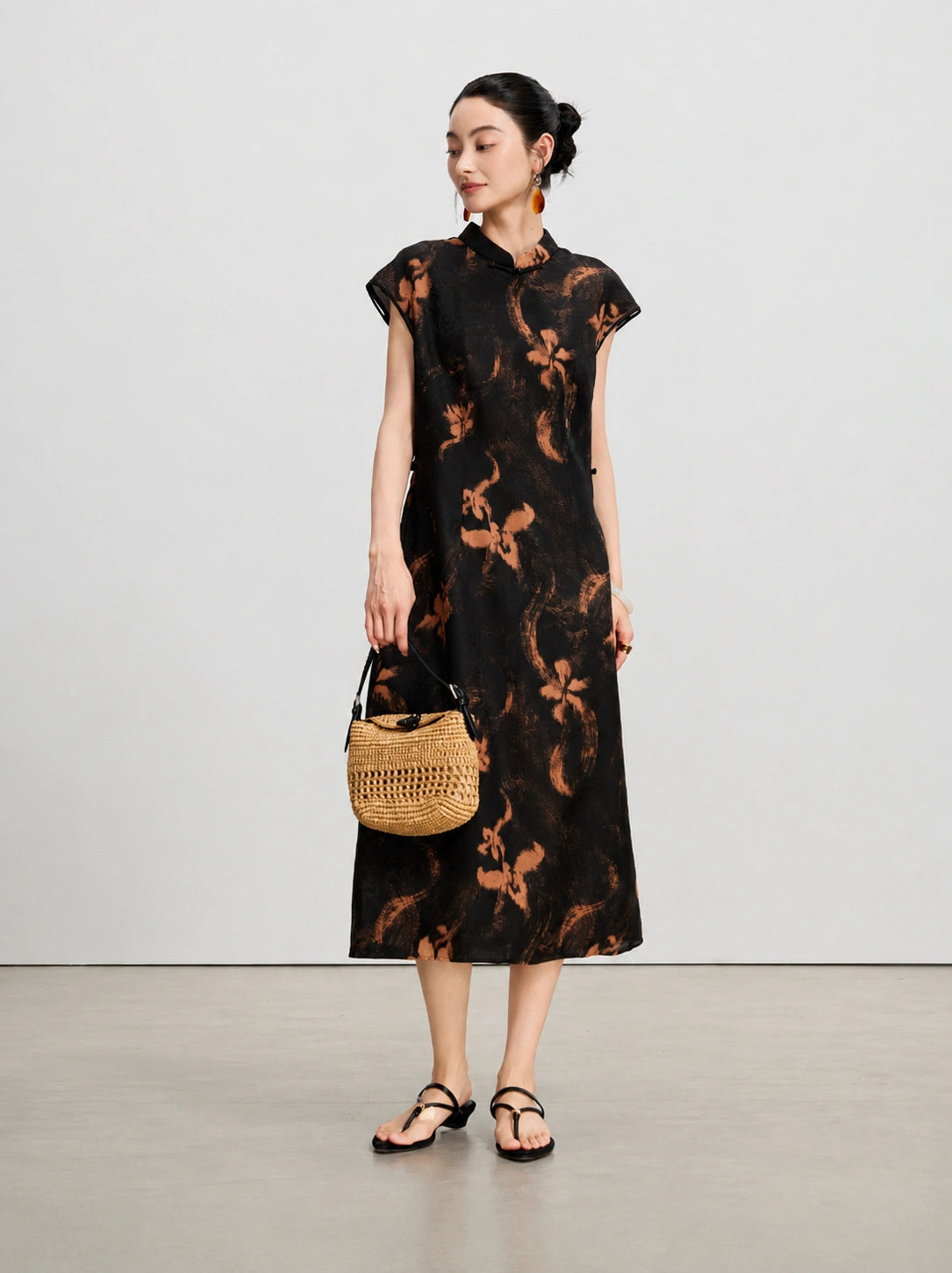 Model wearing a black mulberry silk Xiangyunsha A-line dress with a woven handbag