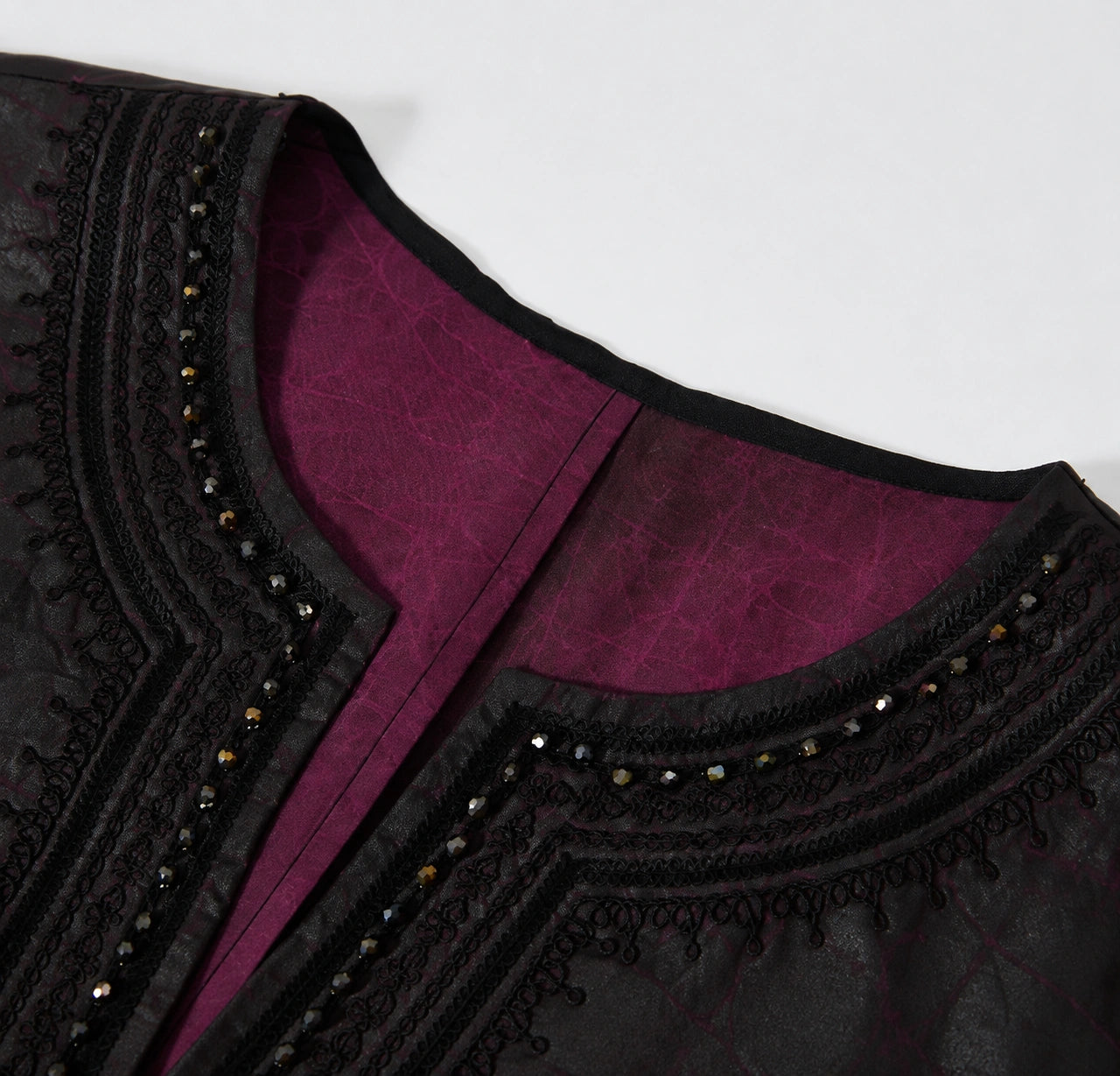 Close-up of the black braided embroidery, faceted beads and purple interior at the V-neckline