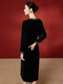Back view of the black velvet dress on a model, showing the waist tie and embroidered cuffs