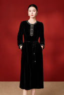 Front view of the model wearing the embroidered black velvet dress with a tie waist
