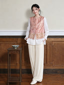 Model wearing the peach jacquard vest over a white blouse with ivory trousers, full-length view