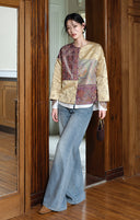 Model wearing the plum and apricot jacket with jeans and carrying a small dark handbag.