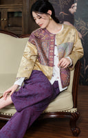 Model seated on a sofa wearing the plum and apricot jacket with purple patterned trousers.
