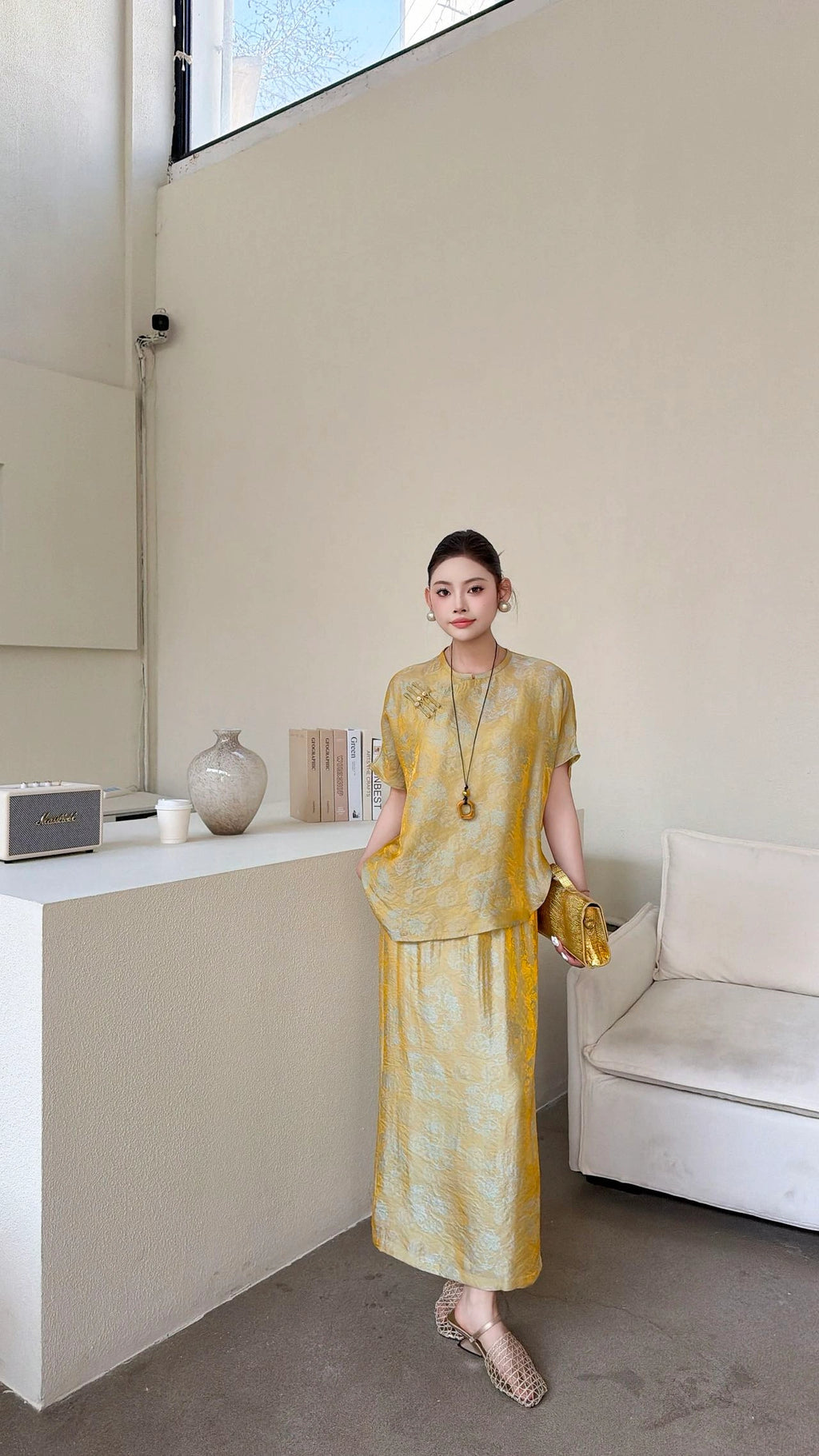 Front view of a gold New Chinese style co-ord set, featuring a short sleeve mandarin collar top with side button detail and a matching maxi skirt with side slit.