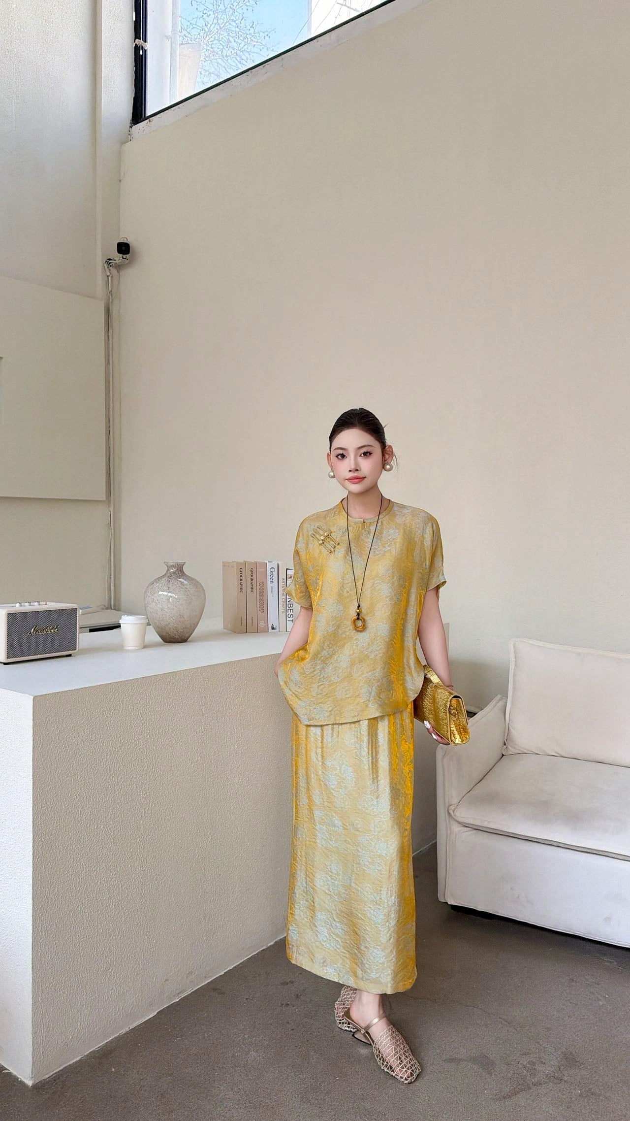 Front view of a gold New Chinese style co-ord set, featuring a short sleeve mandarin collar top with side button detail and a matching maxi skirt with side slit.