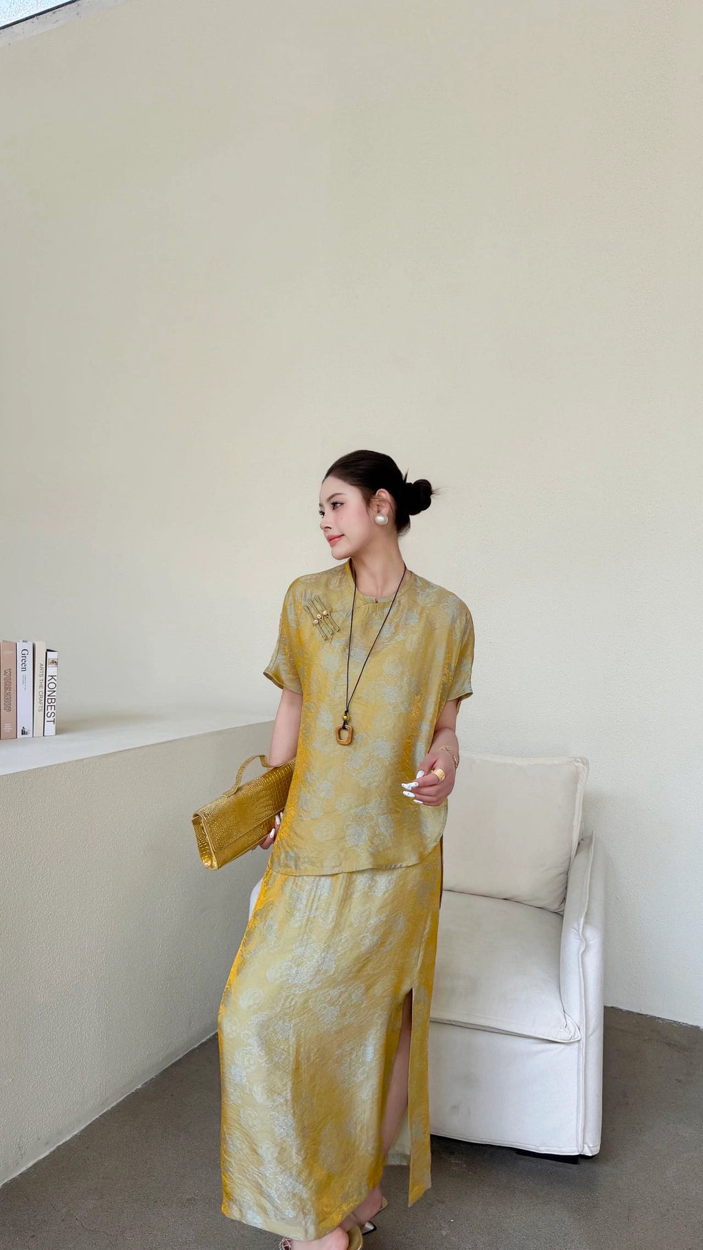 Side view of a woman wearing a gold cheongsam top and skirt set, highlighting the elegant silhouette and the 80% viscose, 20% nylon fabric blend.