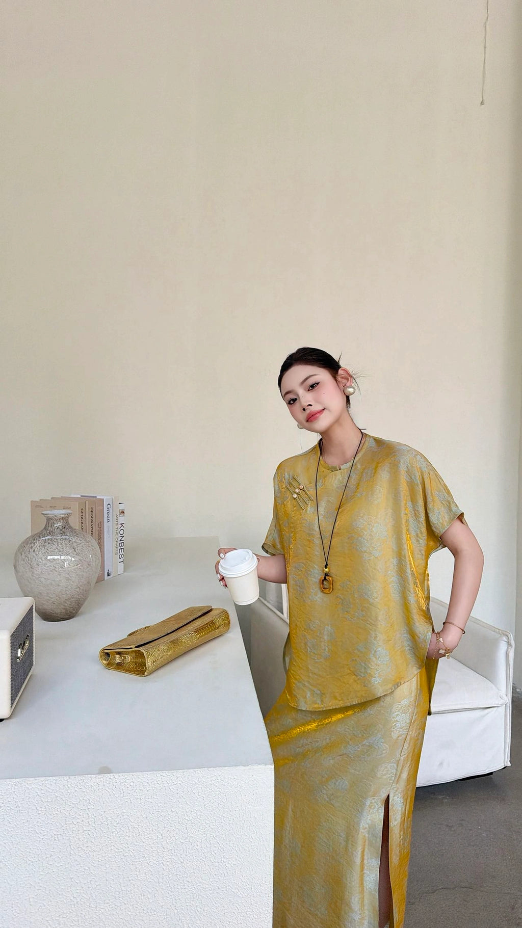 Model holding a coffee cup, wearing a gold short sleeve blouse with a mandarin collar and matching maxi skirt, showcasing the vintage brocade texture.