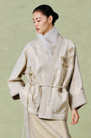 Close view of the jacket’s gold floral embroidery, V-neck opening, waist tie and patch pockets