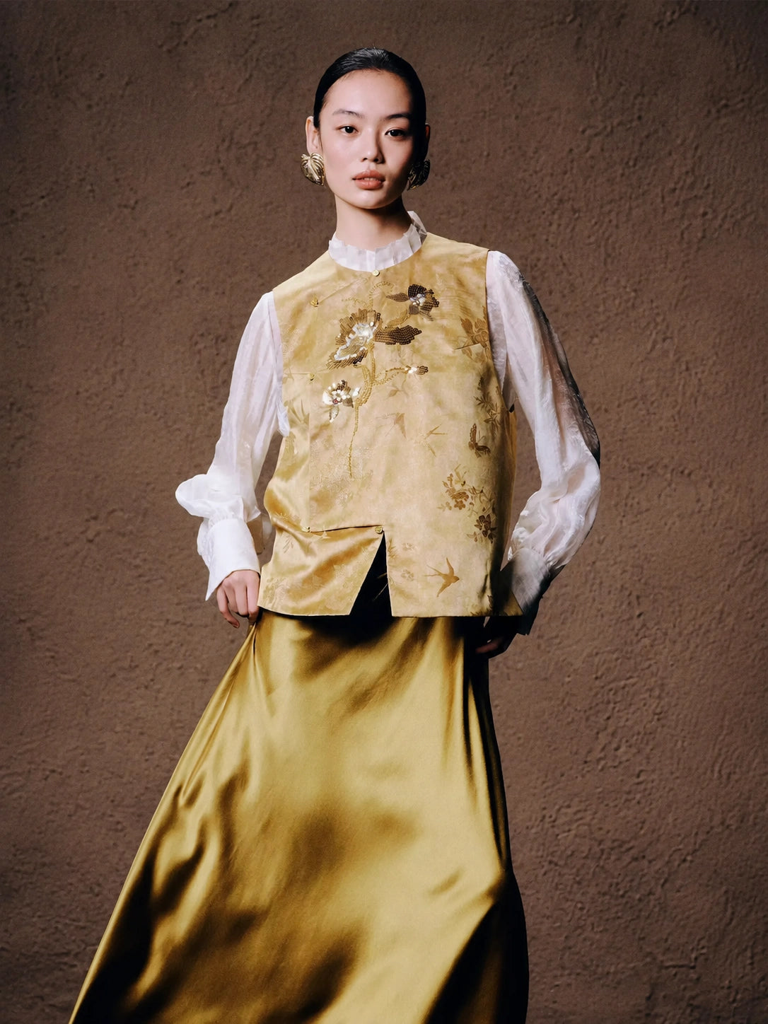 Front view of a women's floral embroidered silk blend vest in golden beige, styled on a model by Gambiered Silk.