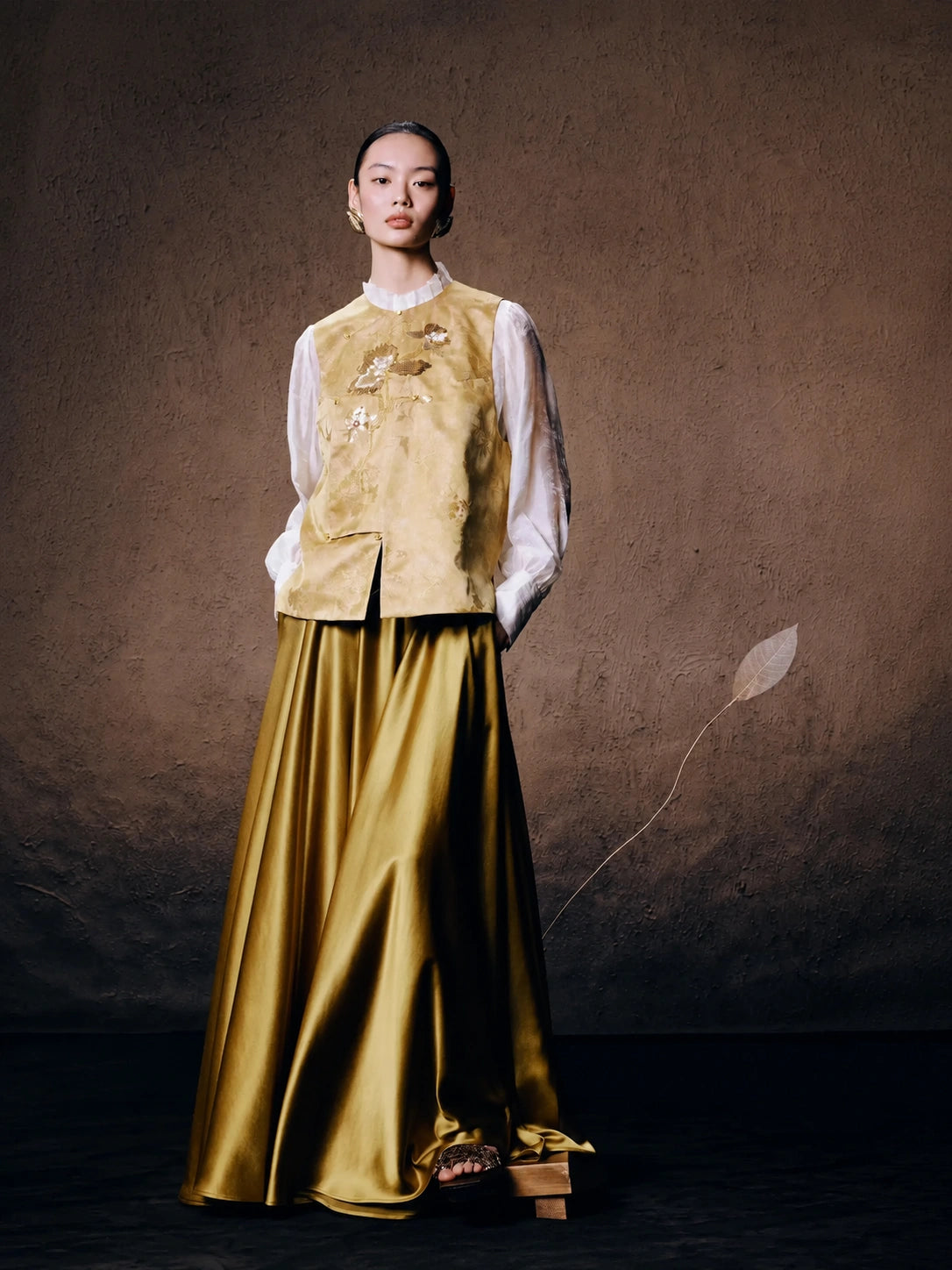 Women's floral embroidered silk blend vest paired with a flowing satin skirt for an elegant oriental-inspired outfit.
